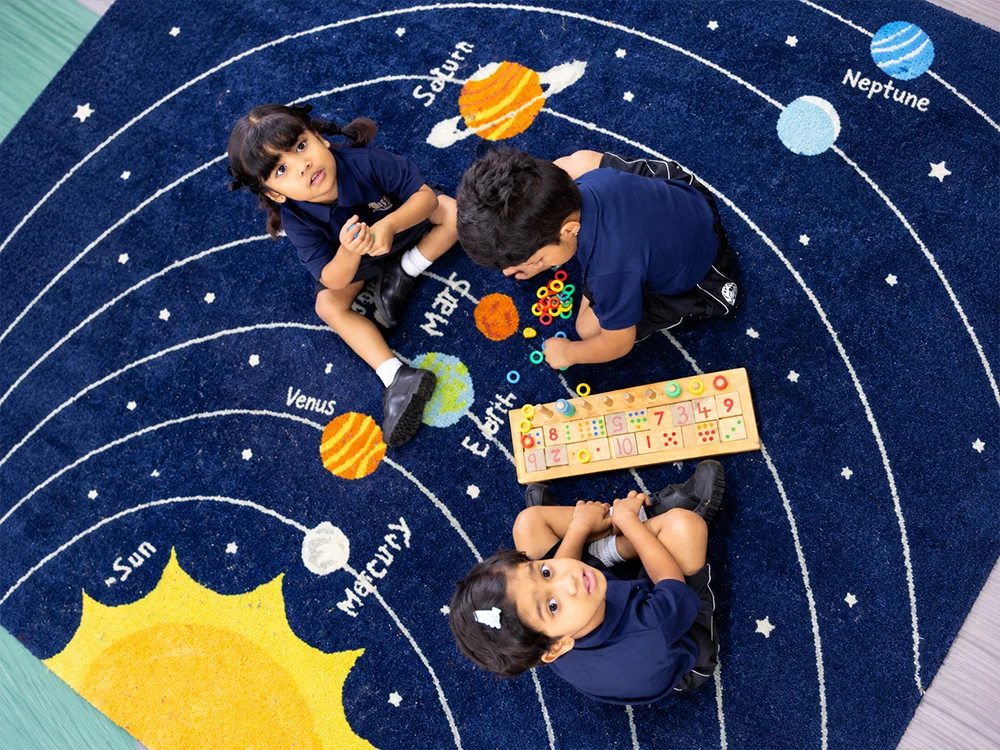 Children exploring a solar system rug