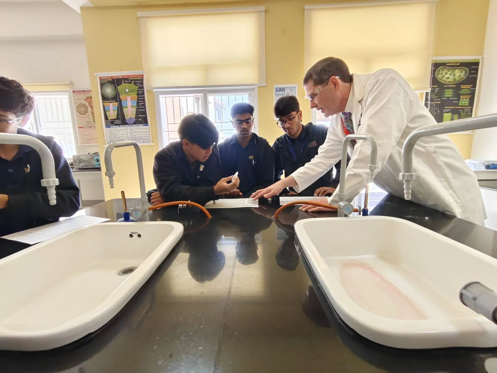 A visiting scientist guiding students through a lab experiment